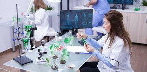 female-scientist-holding-green-solution-while-hear-team-works-background-young-biologist-background-min-1110x550