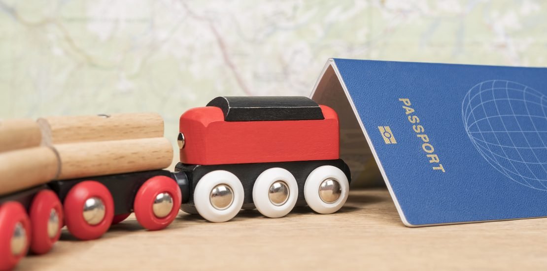 travel-concept-train-enters-tunnel-from-passport-wooden-table-against-background-map-1110x550